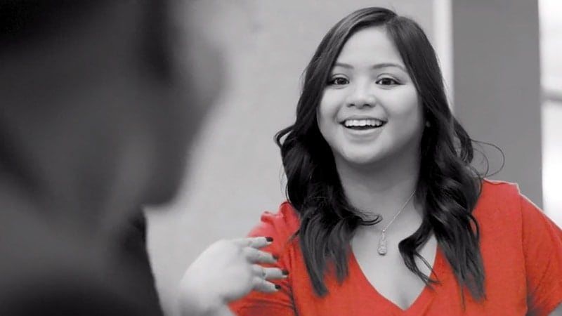 Black and white photo of a person smiling and wearing a red shirt