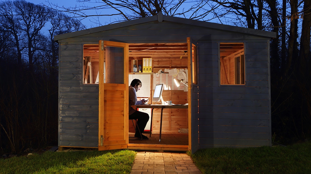 Mann, der in einer Hütte bei Sonnenuntergang am Laptop arbeitet